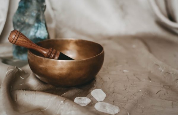 A bronze Tibetan bowl with a mallet on a soft cloth and white stones.