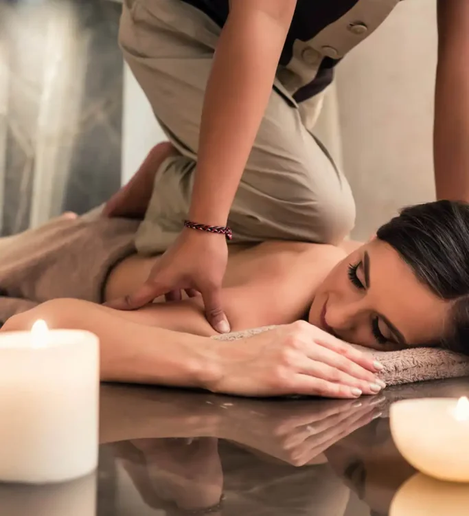 Persona recibiendo un masaje en un entorno relajante con velas encendidas.