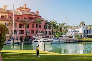 Colorful buildings next to the port of Sotogrande with yachts and palm trees on a sunny day