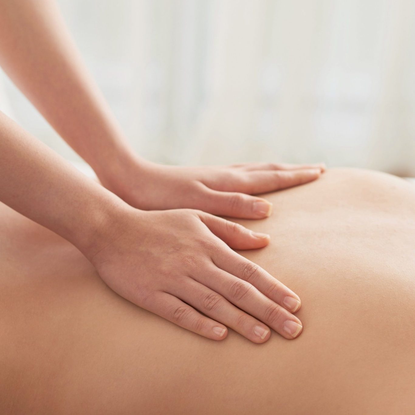 Hands massaging one arm on a soft surface.