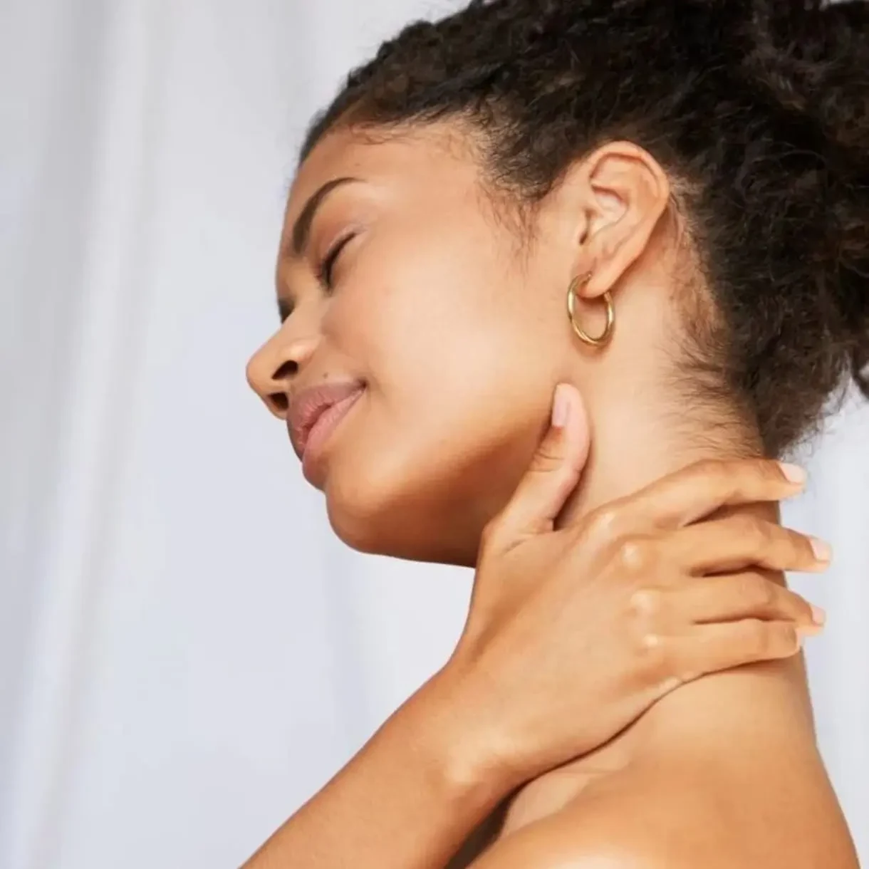 Hands massaging one arm on a soft surface.