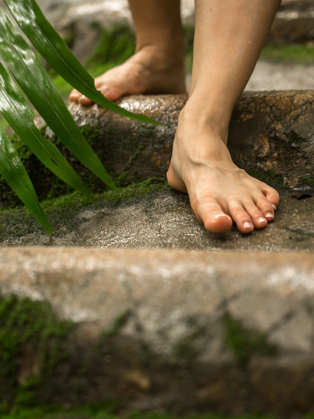 Massage on one foot, with hands gently applying pressure and lighted candles in the background.