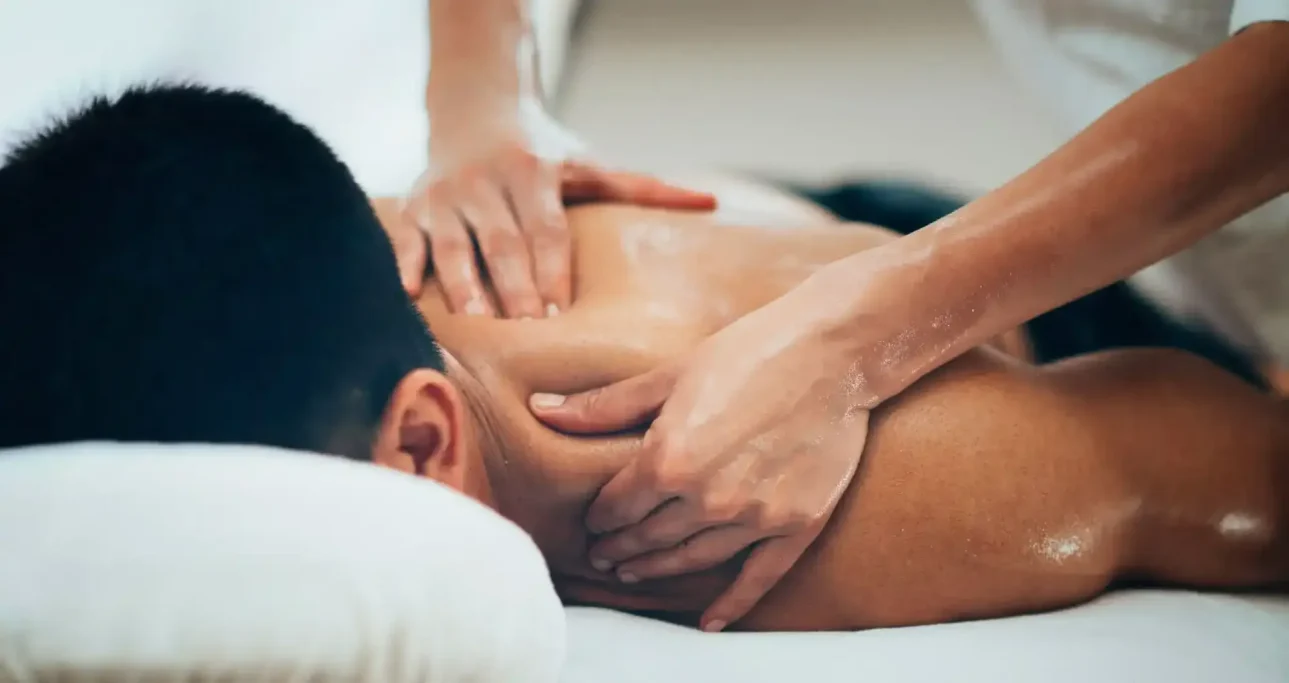Person receiving a back massage, with hands gently pressing the muscles.