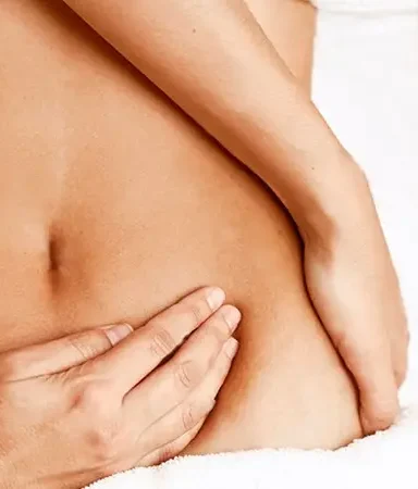 Hand gently touching the skin of an abdomen performing a Detox Massage