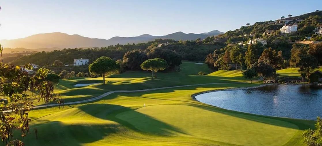 Exclusive golf course at dawn with lake and mountains in the background in Benahavis 