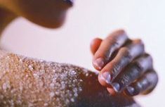 Delicate hand touching a shoulder with salt on the skin.