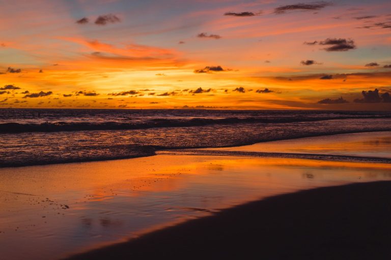 Sunset over Marbella beach, with shades of orange and purple reflected in the water.
