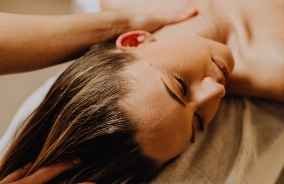 Woman receiving a massage, with her eyes closed and a hand on her neck.