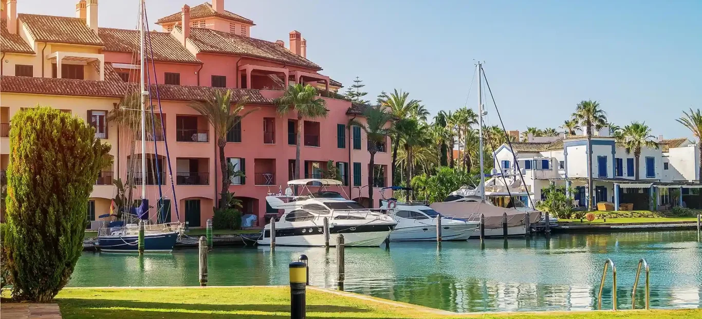 Sotogrande Marina with colourful boats and buildings surrounded by palm trees.