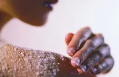 Delicate hand touching a shoulder with salt on the skin.