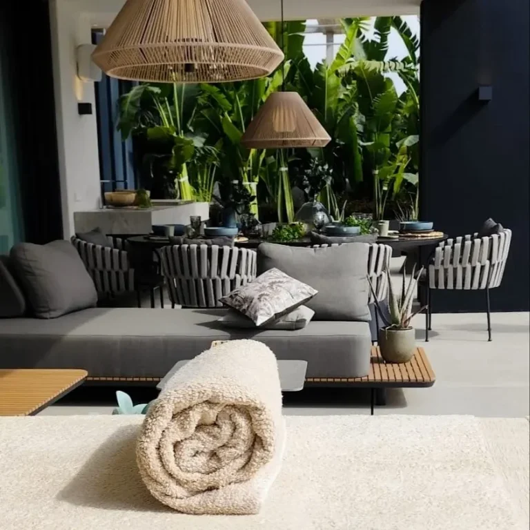 A towel rolled up on a massage table for a home massage on the terrace of a modern villa in Marbella, with a modern-style living room and pl