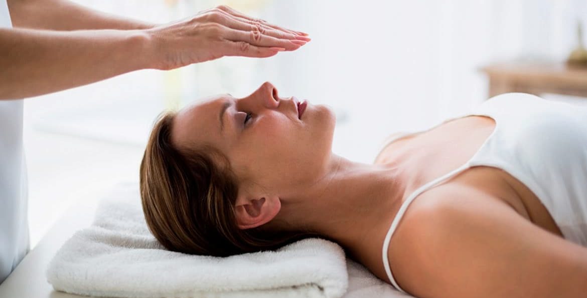 Woman receiving energy healing treatment in a relaxing environment.