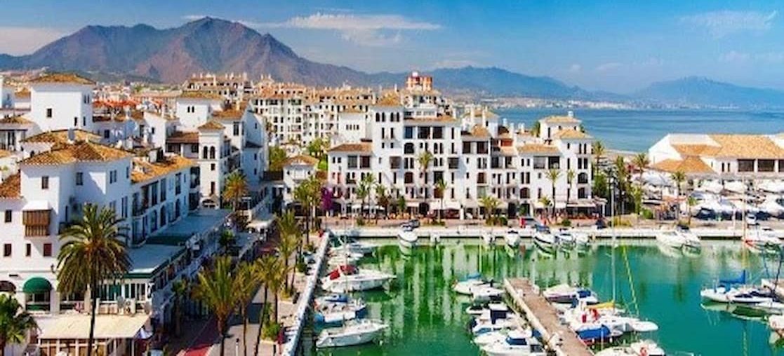 Luxury Home Massage in Puerto Banus Puerto Banús with yachts, white buildings and mountains in the background under a clear sky.