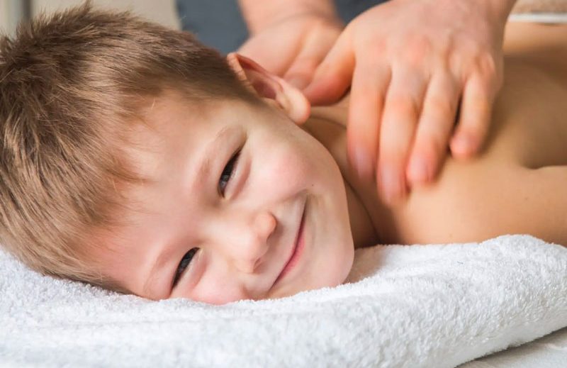 Child smiling while receiving a back massage.