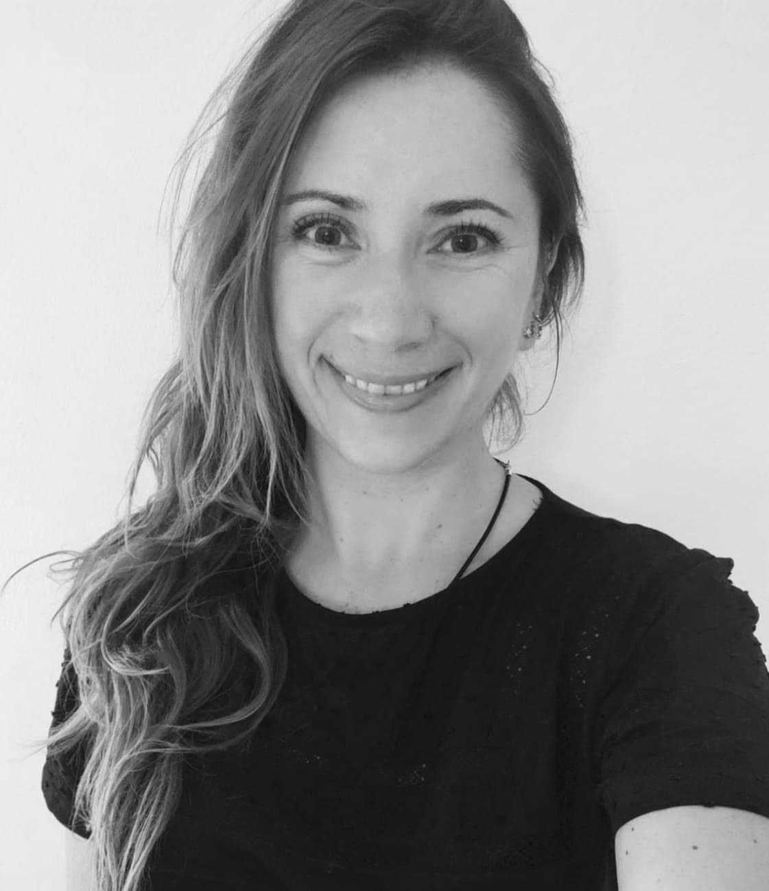 Smiling woman with long, loose hair, wearing a black t-shirt.