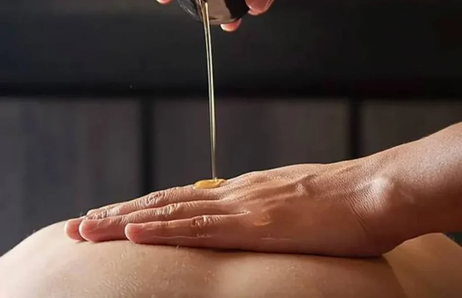 Hand applying oil to the skin, in a relaxing atmosphere.