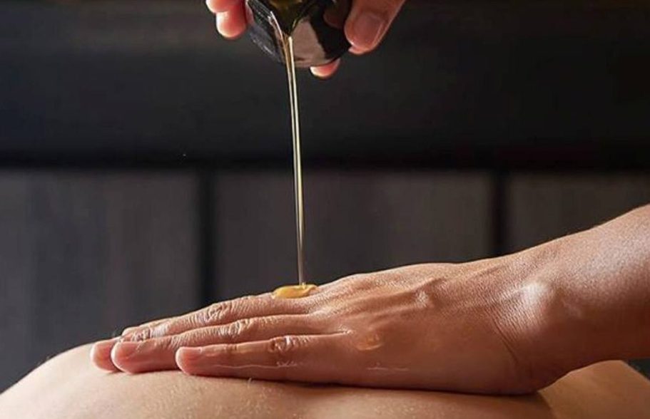 Hand applying oil to the skin, in a relaxing atmosphere.