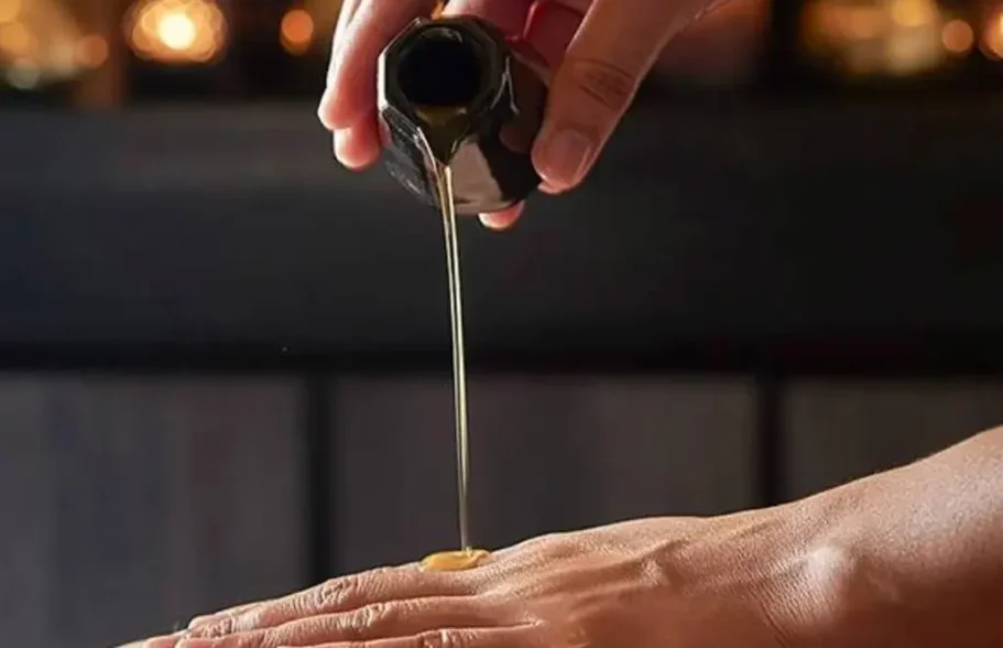 Hand applying oil to the skin, in a relaxing atmosphere.