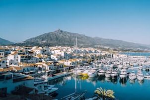 View of the Puerto Banus marina with yachts, white buildings and mountains in the background.