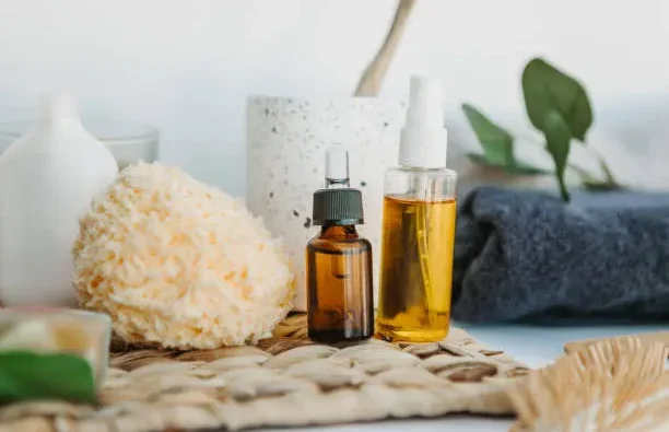 Personal care products: oil bottles, sponge and towel on a table to prepare a spa at home.