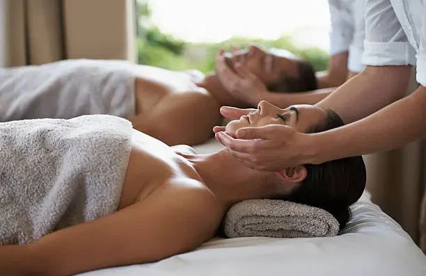 Hand applying oil to the back of a person during a massage at home.
