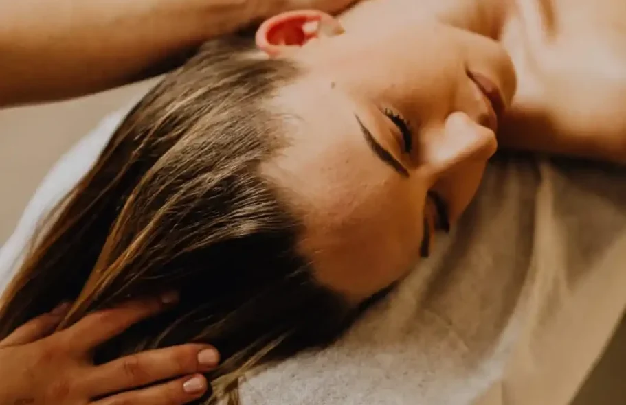 Woman receiving a massage, with her eyes closed and a hand on her neck.