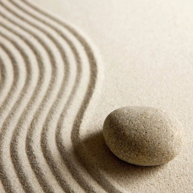 Stone on sand with soft waves created by a rake.