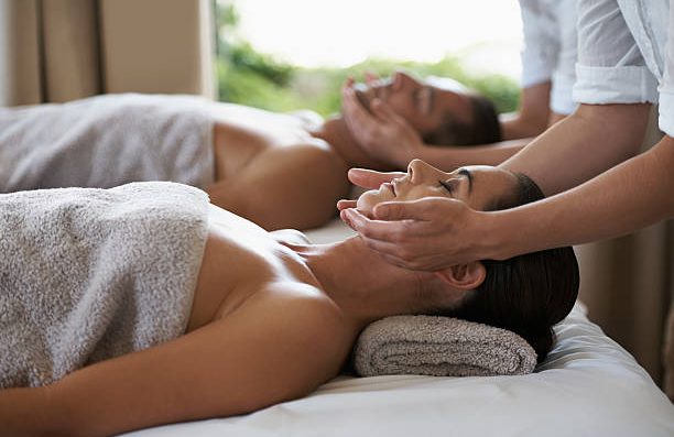 Hand applying oil to the back of a person during a massage at home.