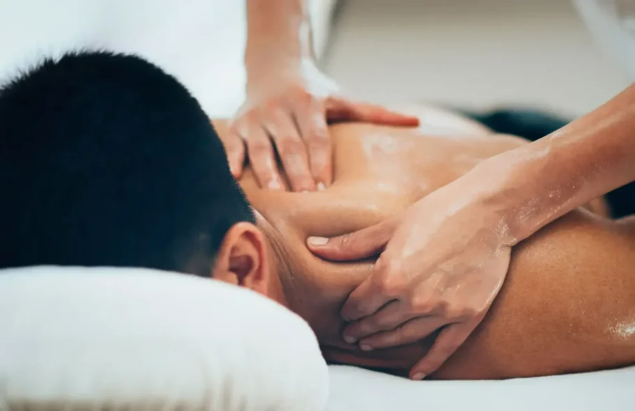 Masseur performing a massage on the back of a person lying down.